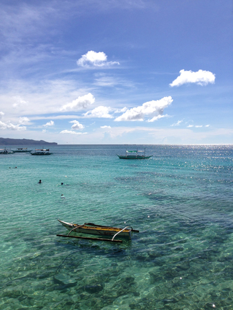 Clear sea with boats and bathers at sunny summer day