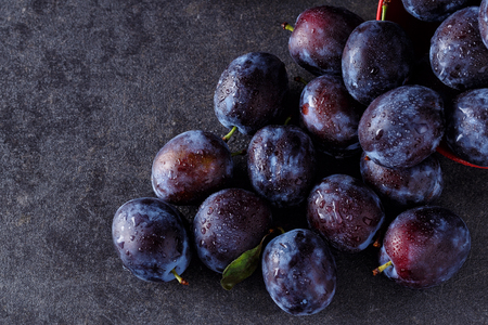 top view fresh ripe plums over dark table backgroundの写真素材