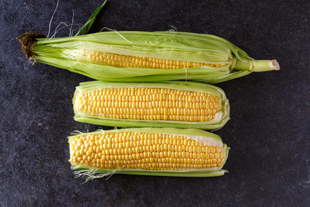 Fresh organic yellow sweet corn on black table-Top view
