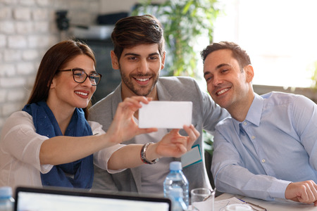 Young designers team take photo on cell phone in officeの写真素材