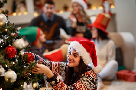 Woman decorates Christmas tree at home for Christmas eveの写真素材