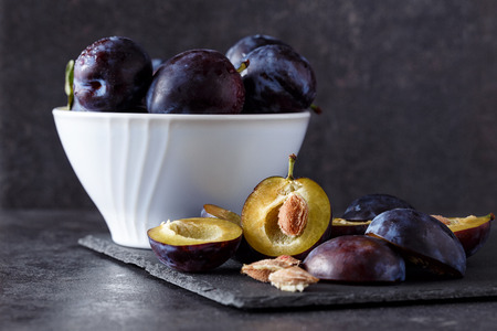 Freshly picked organic plums in bowl on table backgroundの写真素材