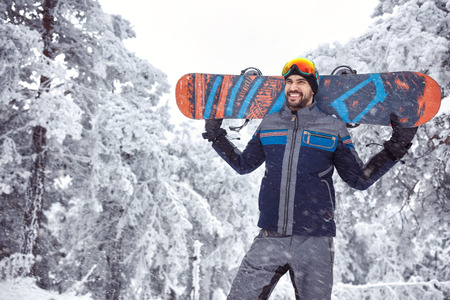 smiling handsome male snowboarder on the mountainの写真素材