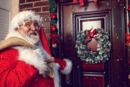 Smiling Santa Claus with sack front of Christmas doorの写真素材