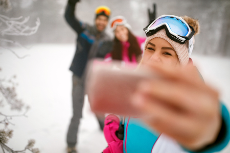 smiling friends making winter selfie in the mountain on winter holidayの写真素材