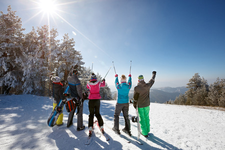Group of skiers on skiing in mountain with ski sticks up, back viewの写真素材