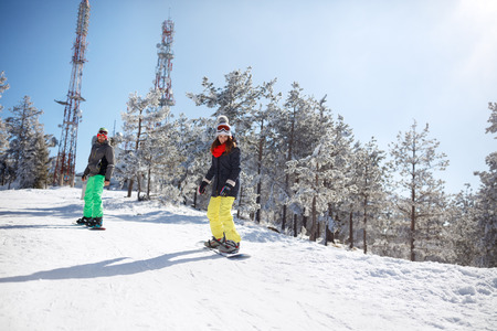 Woman and man snowboarding on snowboard in mountainの写真素材