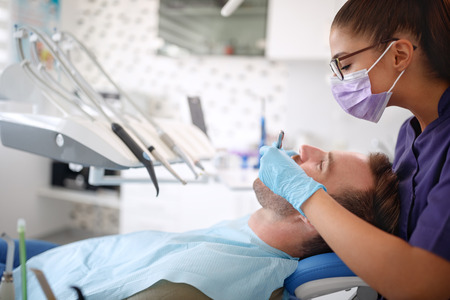 Female dentist working with male patientsの写真素材