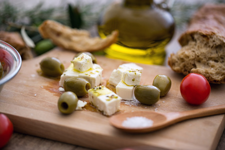 Greek cheese feta with virgin olive oil, green olives and fresh vegetables on wooden table
の写真素材