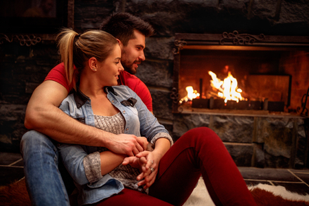 emotional romantic couple hugging at home front of fireplaceの写真素材