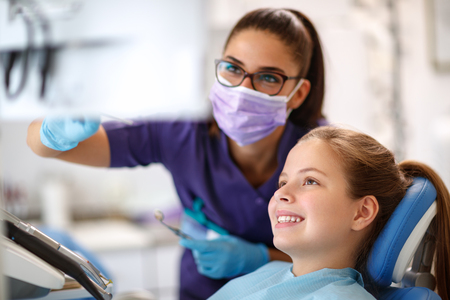 Female child in dental chair with female dentist looking at dental footageの写真素材