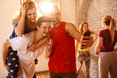 Dancers with friends taking funny selfie together in dancing studioの写真素材