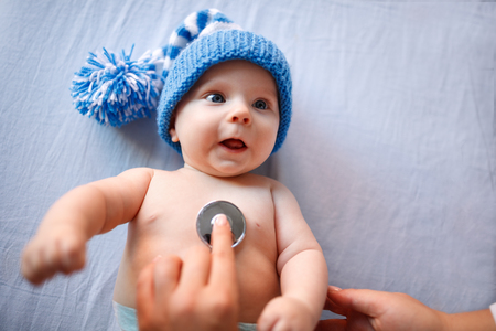 Cute baby with blue cap on preventive pediatric examinationの写真素材