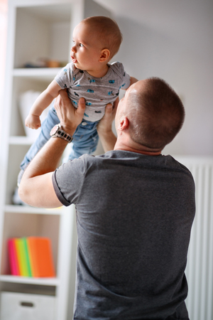 Father raises up cute male baby in handsの写真素材