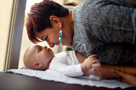 Smiling mother with her baby boy enjoying and playing- family happiness, love and care concept
