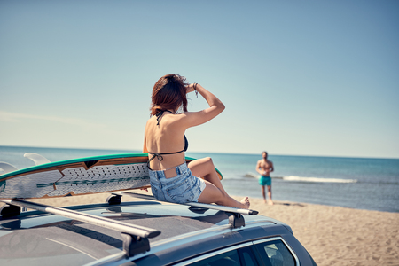 beautiful surfer girl sitting on the car and getting ready for surfing Vacation. Extreme Sportの写真素材