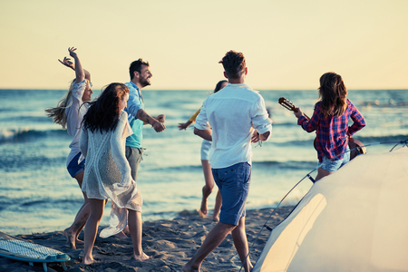 Party on beach- happy young people dancing together at the beach on beautiful summer sunsetの写真素材