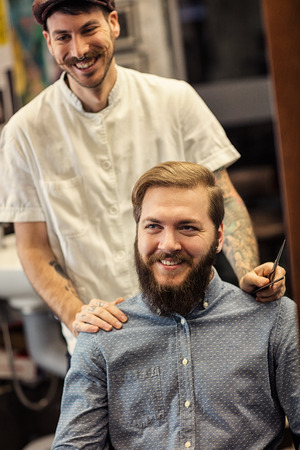 smiling male barber and satisfied customers in mirrorの写真素材