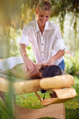 Massage therapy, healthcare concept, young woman lying on massage bed receiving a treatment from a masseur in natureの写真素材