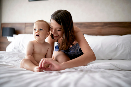 Enjoying morning together. Happy loving family. Smiling mother and her child son on the bedの写真素材