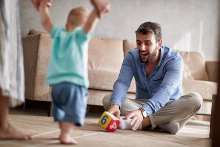 Happy parents playing with their baby. First steps, family, parenthood and peopleの写真素材