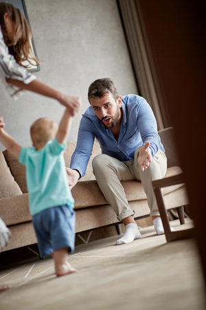young mother and father at home learns to walk their child boy the first stepsの写真素材