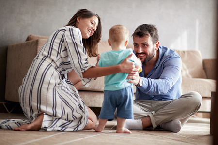 Happy family - mother and father playing with a baby boy at homeの写真素材