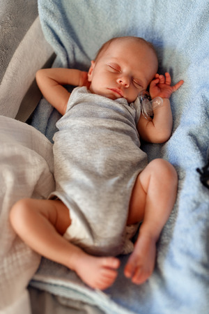Cute baby boy sleeping in the bouncerの写真素材