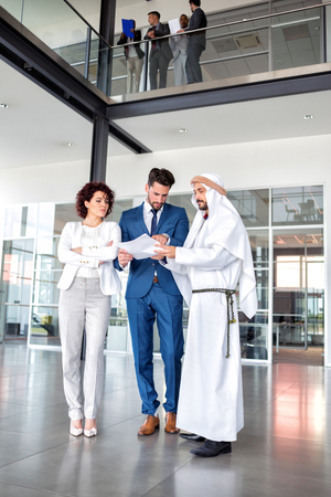 Unsatisfied young managers on meeting with Arabian businessman, full lengthの写真素材