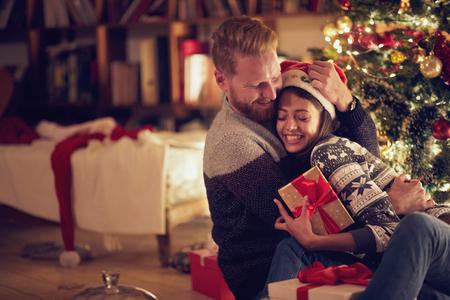 smiling couple hugging by Christmas treeの写真素材