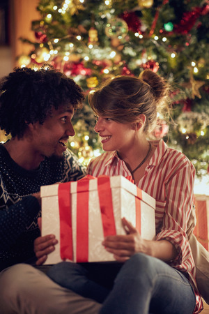 Romantic man and girl exchanging Christmas presents and enjoying in holidaysの写真素材