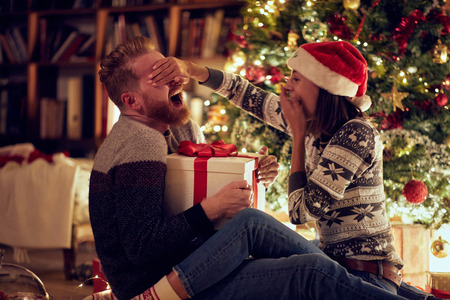 romantic holiday surprise â Young romantic man and woman in love at Christmas nightの写真素材