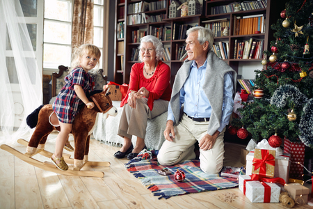 Cheerful grandparents and little happy girl together for Christmasの写真素材