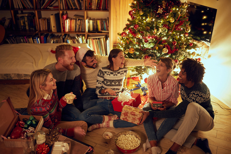 Happy friends laughing and sharing Christmas gifts.の写真素材