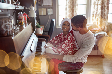 Happy young father with child girl on Christmas play music on piano.の写真素材