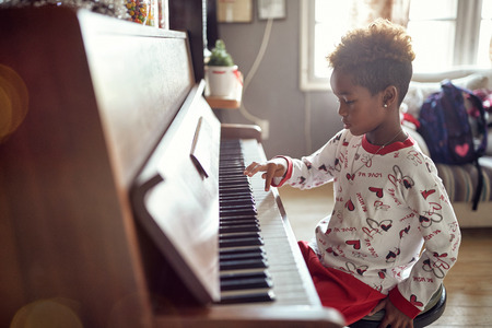 beautiful little girl is playing on piano x-mas music. Concept Christmas, New Year, holiday, family happiness, childhood.の写真素材