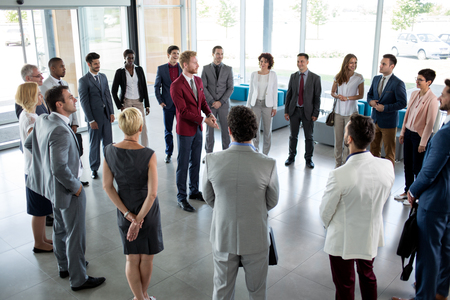 young leader standing in circle of his successful business teamの写真素材