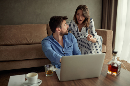 Woman and man enjoying time together browsing on laptop at homeの写真素材