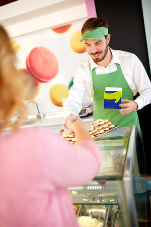 Confectionery salesman showing nice cookies on plateの写真素材
