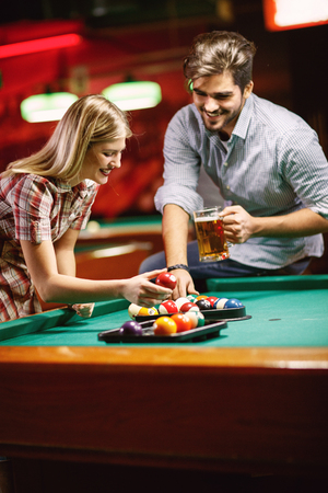 young smiling couple sorting balls for beginning billiard gameの写真素材