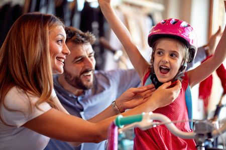 Family buying new bicycle for happy little girl in bike shopの写真素材