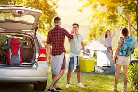 Young people say hello to just arrived friends on a camping tripの写真素材