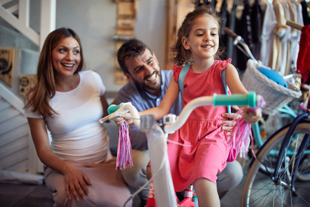 Father and mother choice new bicycle for happy little girl in bike shopの写真素材