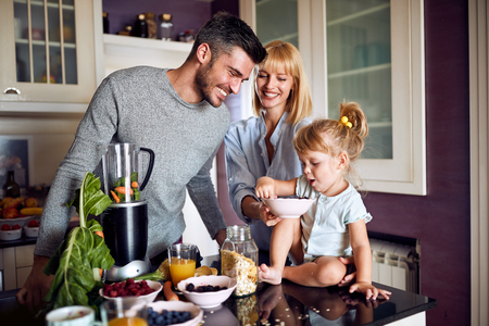 Cheerful family with daughter eating and having fun in kitchenの写真素材