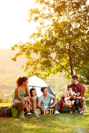 young people on camping trip to play and sing, relaxing on vacationの写真素材