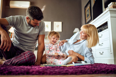 Cute child showing puzzle to her young parentsの写真素材
