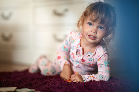 Cute little girl with big blue eyes on floorの写真素材