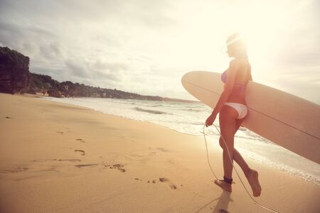 Attractive girl surfer with  surfboard on sunny beach