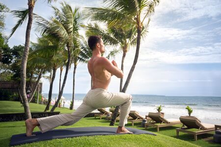 Young handsome healthy yoga man doing yoga on beachの写真素材