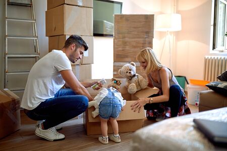Happy family unpacking cardboard boxes in their new homeの写真素材
